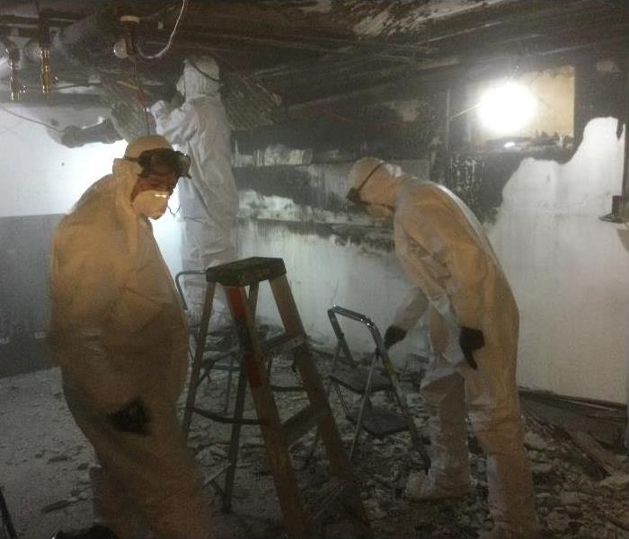 Technicians in PPE removing debris from a fire damaged room