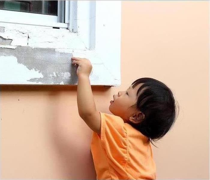 child touching a window with pealing paint